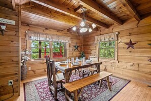 A wooden cabin interior with a dining table set for four, a bench, and a chandelier. - Epic Views | Hot Tub | Minutes to Pigeon Forge (Sevierville)