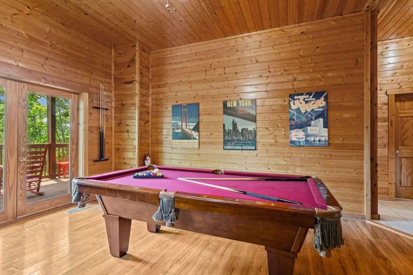 Una mesa de billar en una sala de madera con carteles en la pared.