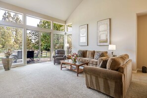 A spacious living room with a large window, a sofa set, a coffee table, and a lamp.