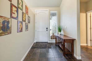 A hallway with a white door, a wooden bench, and a rug.