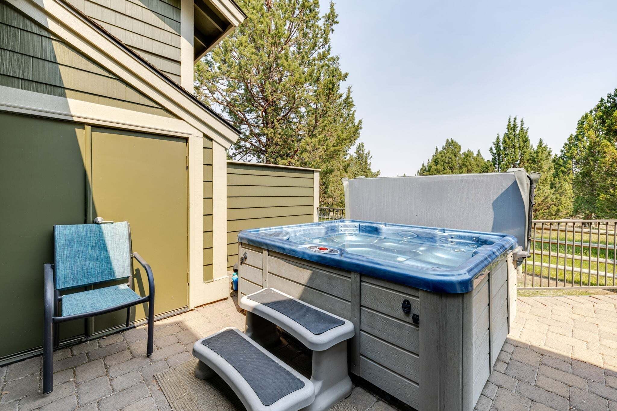 Un jacuzzi extérieur avec des marches menant à celui-ci, une chaise et un espace abrité.