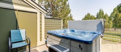 Un jacuzzi extérieur avec des marches menant à celui-ci, une chaise et un espace abrité.