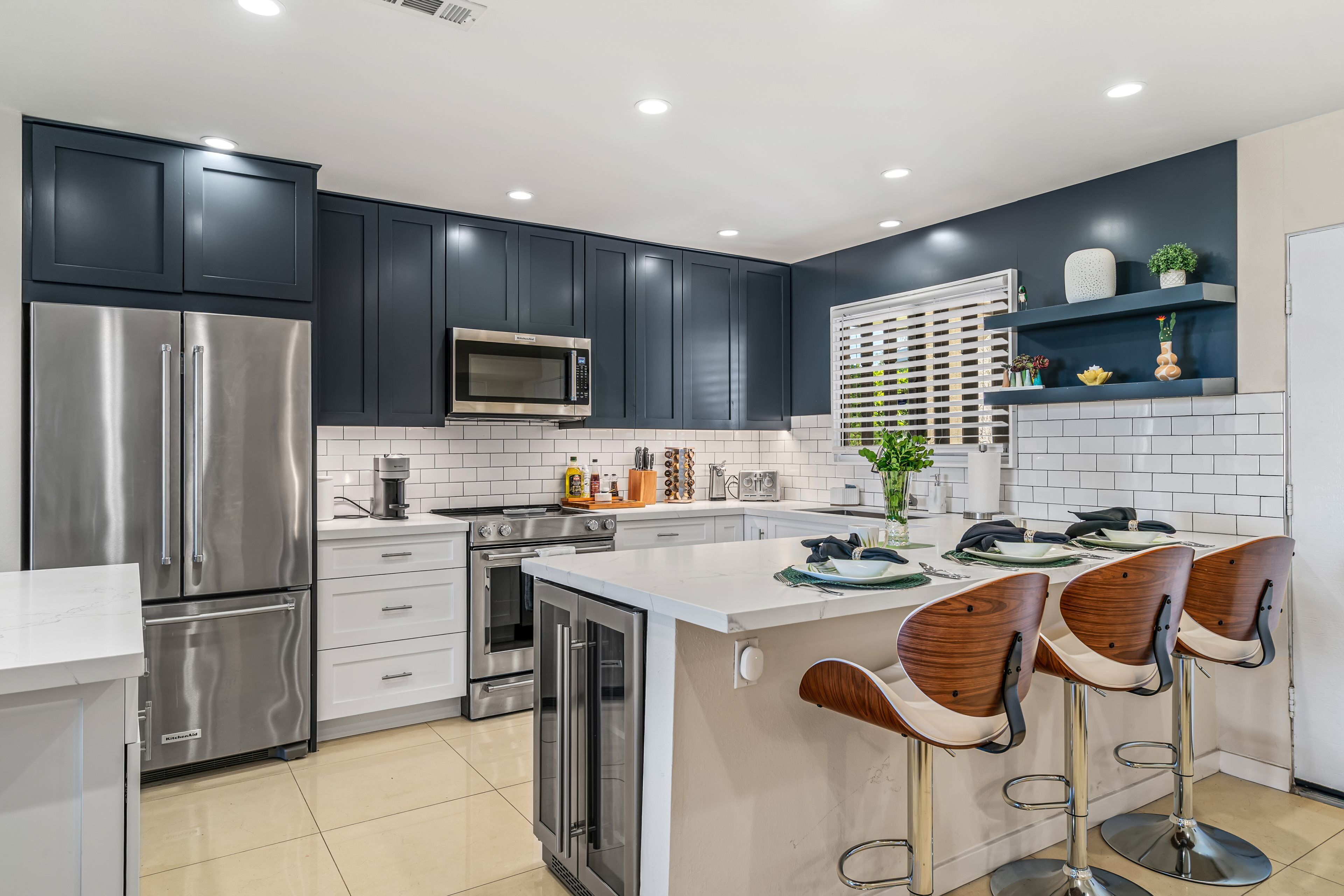 A modern kitchen with dark cabinets, stainless steel appliances, and a central island with bar stools.