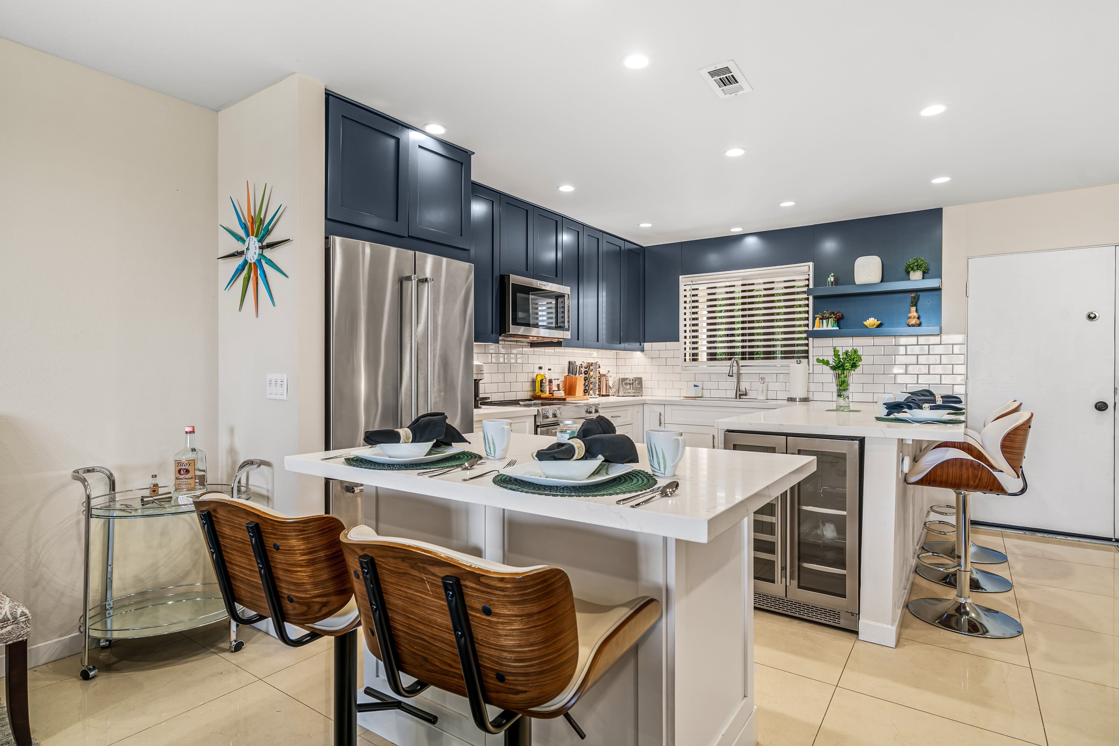 A modern kitchen with a central island, stainless steel appliances, and dark cabinetry.