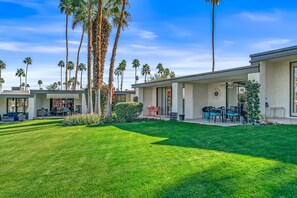 A residential property with a well-maintained lawn, multiple palm trees, and a patio area with outdoor furniture. - Desert Elegance Off El Paseo (Palm Desert)