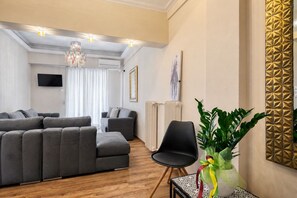 A modern living room with a sectional sofa, a black armchair, and a potted plant. - Luxury 4-bed Myrto apartment near Onassis Stegi - sleeps 10, 4.5 baths (Athina)