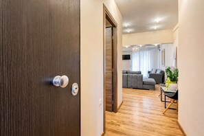 Un salon moderne avec un canapé gris, une petite table sur laquelle est posée une plante, et un plancher en bois.