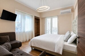 Une chambre à coucher avec un lit, un canapé, une télévision et une armoire.