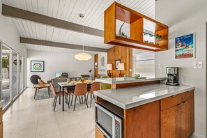Een moderne keuken met een centraal eiland, houten kasten en een eethoek met uitzicht.