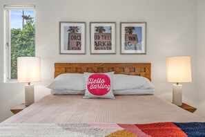 A bedroom with a bed, two bedside lamps, a headboard, and three framed pictures on the wall. - The Orchid Tree Inn, Est. in 2026, Central Palm Springs, A Mid-Century Beauty (Palm Springs)
