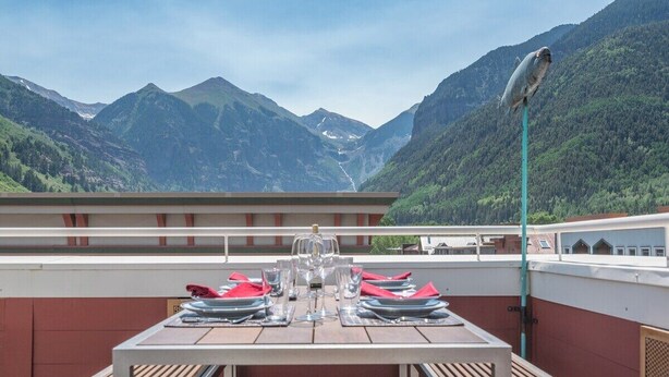 A dining table set with glasses and cutlery, overlooking a mountainous landscape. - Diamondtooth 3 3 Bedroom/ 3 Bathroom Downlown Condo (Telluride)