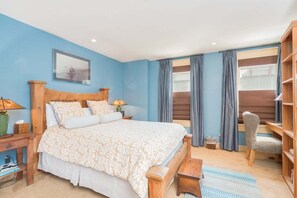 Een slaapkamer met een bed, nachtkastjes, een stoel, een bureau en een boekenkast.