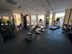Een sportschool met diverse fitnessapparaten, waaronder banken en loopbanden.