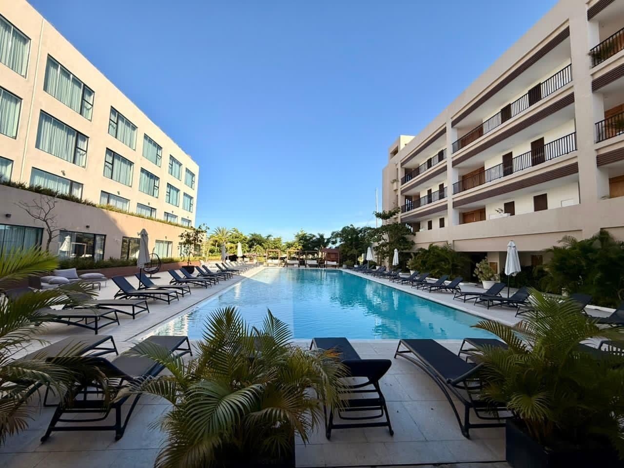 Un espace piscine d’hôtel avec des chaises longues et une piscine à l’eau d’un bleu limpide.