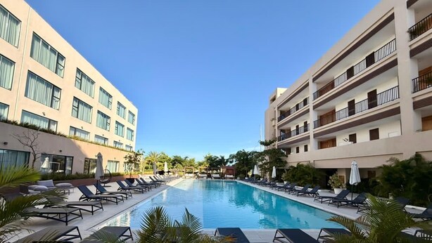 Et hotelområde med swimmingpool, liggestole og krystalklart vand.