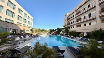 Un espace piscine d’hôtel avec des chaises longues et une piscine à l’eau d’un bleu limpide.
