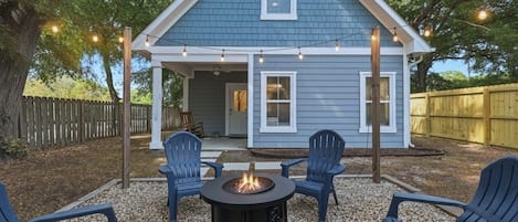 A house with a covered porch, outdoor seating, and a fire pit.