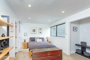 Een slaapkamer met een bed, nachtkastjes, een ventilator en een raam.