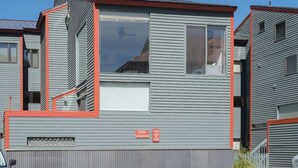 A modern multi-story residential building with a grey exterior and red accents. - Telluride Lodge Condo 323 (Telluride)