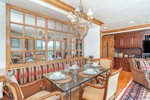 A dining area with a glass table, wooden chairs, and a bench with a patterned cushion. - Penthouse At The Peaks 744 (Mountain Village)