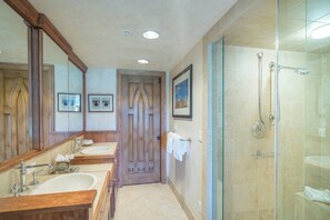 A bathroom with two sinks, a shower, and a door with a mirror. - Penthouse At The Peaks 744 (Mountain Village)