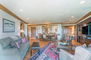 A spacious living room with a large rug, a sofa, a coffee table, and a television. - Penthouse At The Peaks 744 (Mountain Village)