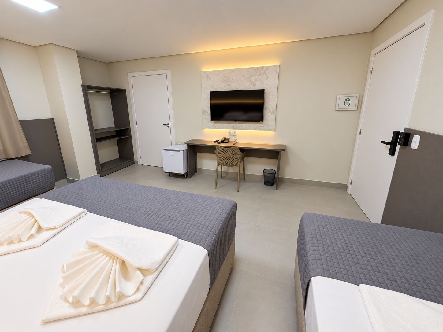 Habitación de hotel con dos camas, un escritorio, un televisor y un armario.
