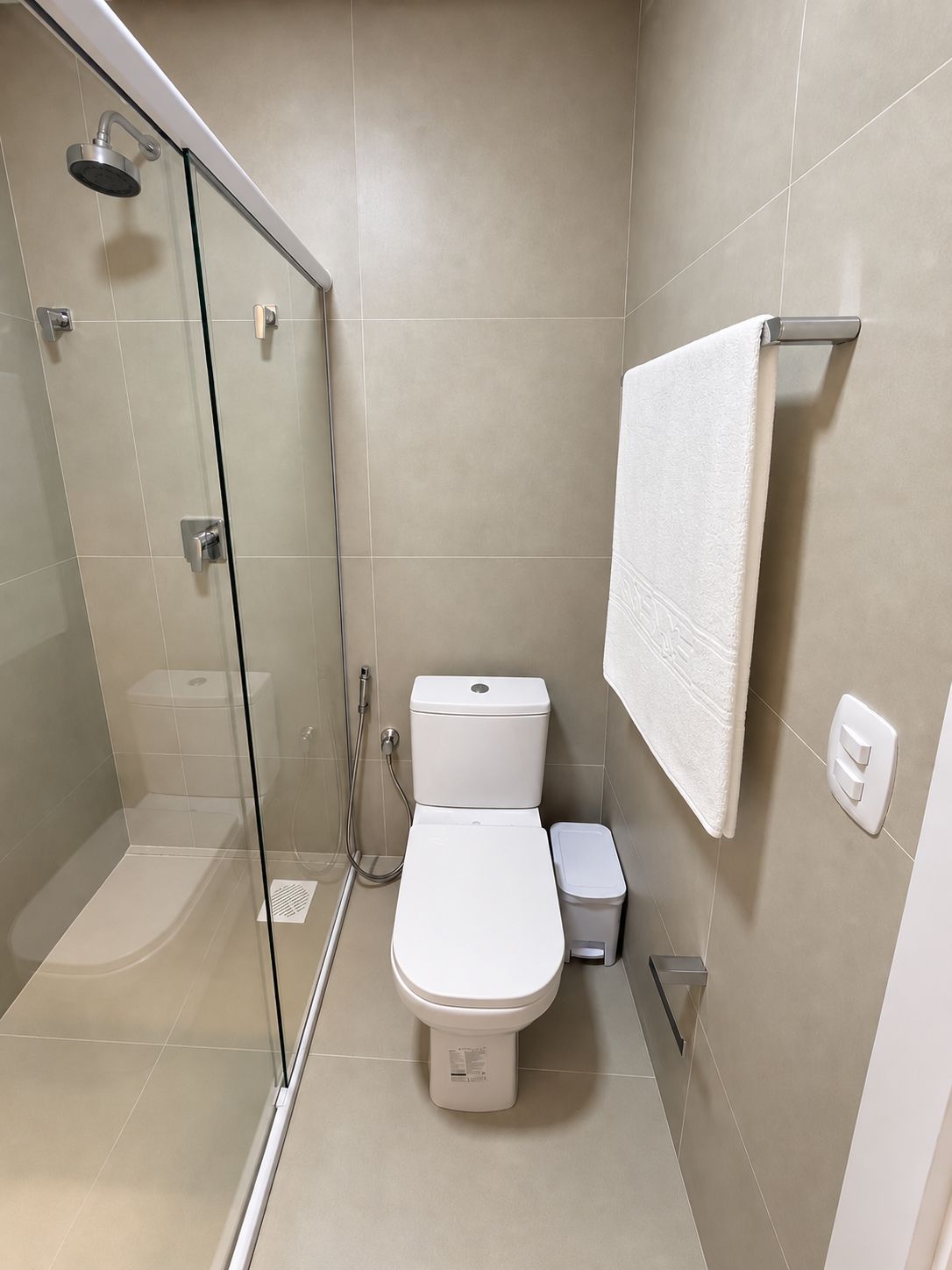 Un baño moderno con ducha de vidrio, inodoro y toallero.