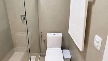 Un baño moderno con ducha de vidrio, inodoro y toallero.