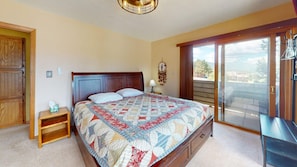 Ein Schlafzimmer mit Bett, Nachttisch, Kommode, Traumfänger und Blick ins Freie.