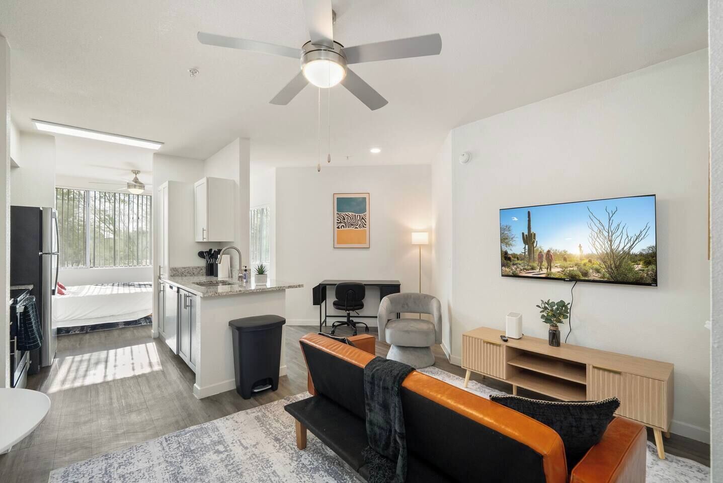 A modern living room with a sofa, a TV, and a ceiling fan.