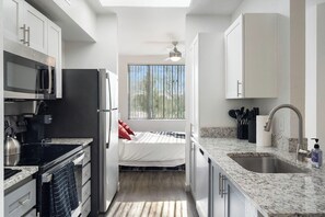 A compact kitchen with a microwave, stove, refrigerator, and sink. - Bright Tempe Studio • Green Views • 5 Min to A (Tempe)