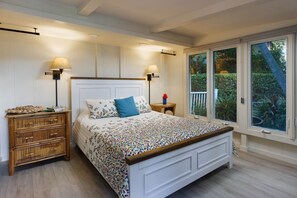 Un dormitorio con cama, mesitas de noche y ventana con vistas a zonas verdes.