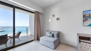 A balcony with a view of the sea, a sofa, and a TV on the wall. - Two 1001A Studio -Stylish Beachfront studio with Stunning Ocean Views (Puerto Peñasco)