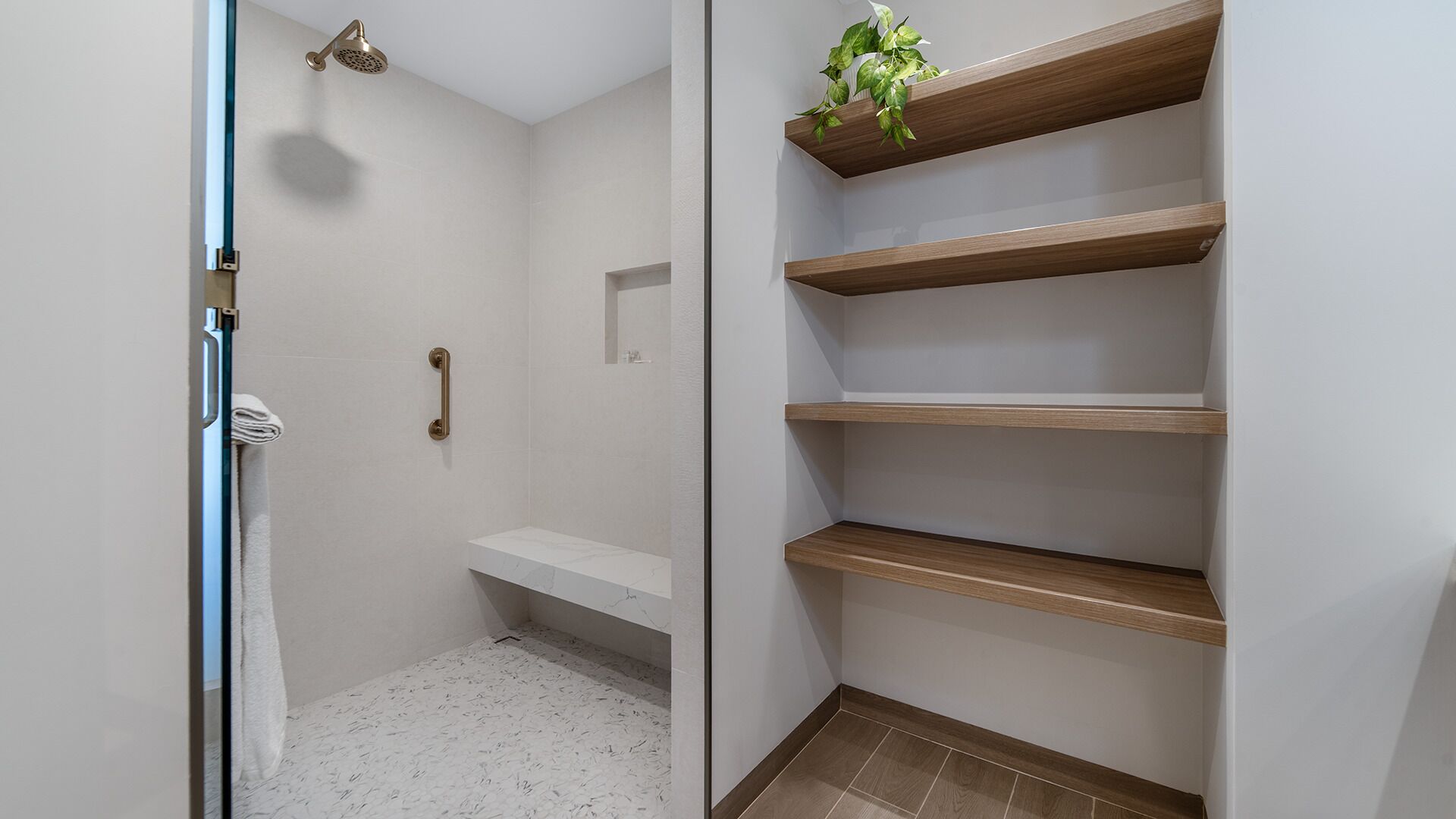 Un bagno con doccia, WC e lavandino. Sono presenti mensole in legno a parete.