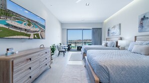 Une chambre d’hôtel moderne dotée d’un grand lit, d’un bureau et d’un balcon offrant une vue sur la mer.