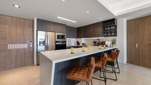 A modern kitchen with a central island, bar stools, and built-in appliances. - Two 406 - Sea Luxe 1 bedroom condo (Puerto Peñasco)