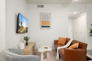 A modern living room with a sofa, armchair, coffee table, and artwork on the wall. - Chic Tempe Studio • Pool+Fast Wi-Fi • 5 Min to (Tempe)