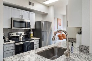 A modern kitchen with stainless steel appliances, granite countertops, and a built-in oven. - Chic Tempe Studio • Pool+Fast Wi-Fi • 5 Min to (Tempe)