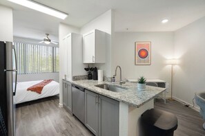 A compact kitchen with granite countertops, a built-in dishwasher, and a small dining area with a table and chairs. - Chic Tempe Studio • Pool+Fast Wi-Fi • 5 Min to (Tempe)