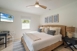 Une chambre à coucher avec un lit, un bureau, une chaise, une fenêtre et un ventilateur de plafond.