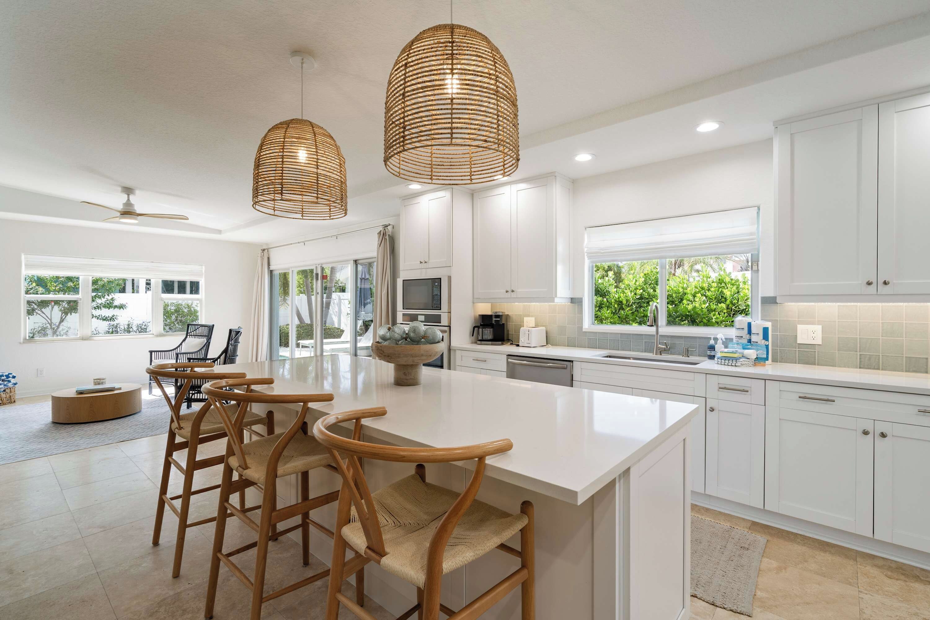 A modern kitchen with white cabinetry, a central island with bar stools, and pendant lighting.