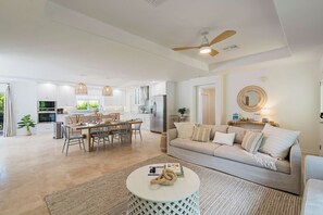 A spacious living area with a sofa, coffee table, and a dining table with chairs. - Latitude Adjustment by SeaBreeze Vacation (Holmes Beach)