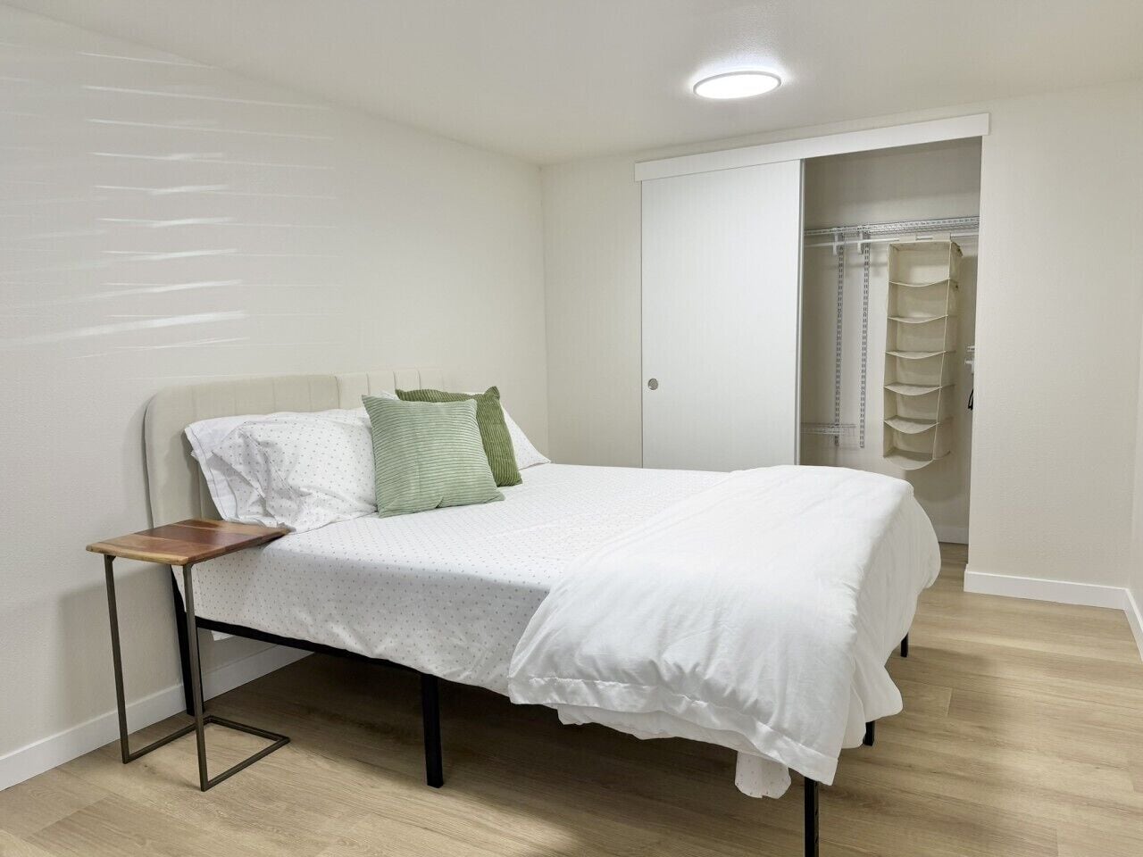 A bedroom with a bed, a bedside table, and a wardrobe.