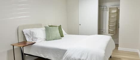 A bedroom with a bed, a bedside table, and a wardrobe.