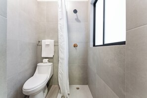 A small, modern bathroom with a toilet, a shower, and a window. - Suite | Polanco | Relax (Ciudad de México)