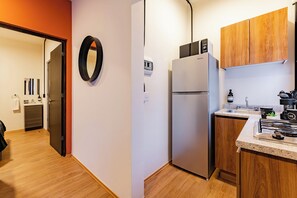 A modern kitchen with a built-in refrigerator, wooden cabinets, a stainless steel sink, and a countertop with a kettle and a coffee machine. - Suite | Polanco | Relax (Ciudad de México)