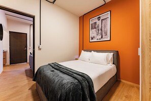 Un dormitorio con cama, una puerta y un cuadro colgado en la pared.