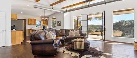 A spacious living room with a large leather sectional sofa, a cowhide rug, and a ceiling fan.