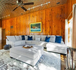 Uma sala de estar moderna com sofá seccional, mesa de centro e quadro de um cavalo na parede.